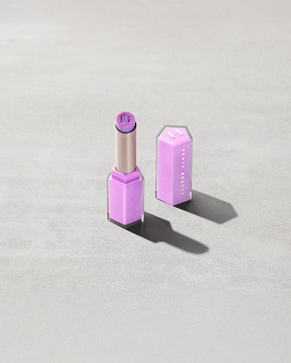 Open product shot of Gloss Bomb Stix Shimmer in shade Ice Amethyst on a concrete background.